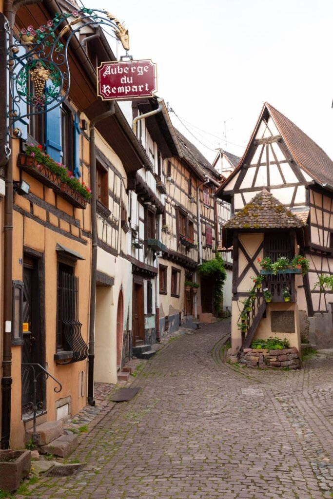 A narrow cobblestone lane lined with colourful half-timbered houses in Eguisheim, France.