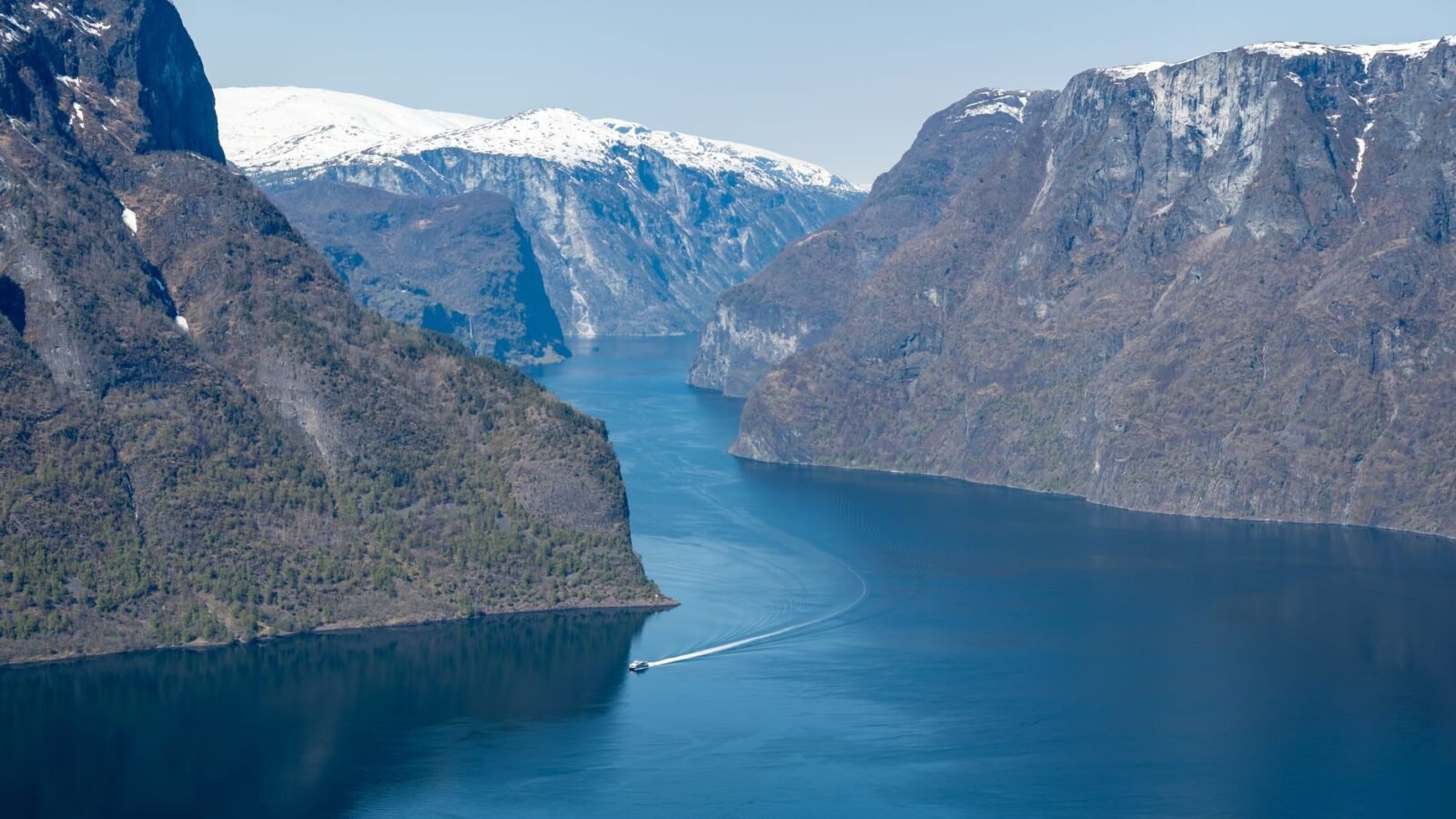 Calm water between steep green and rocky mountains at Aurlandsfjord in Norway.