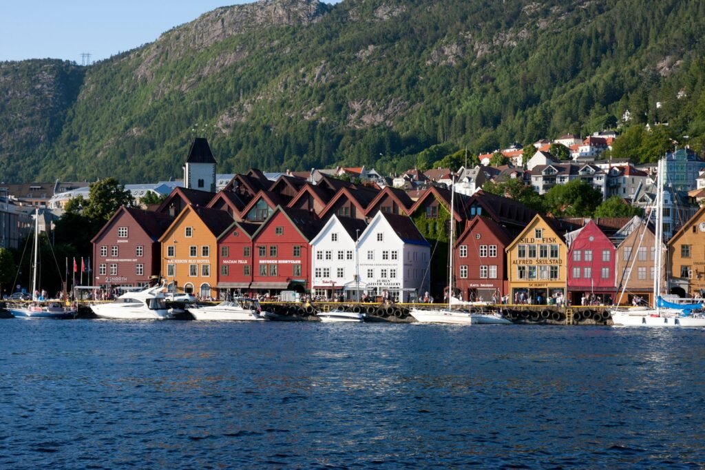 Colourful historic waterfront buildings, boats and green mountains in Bergen, Norway.
