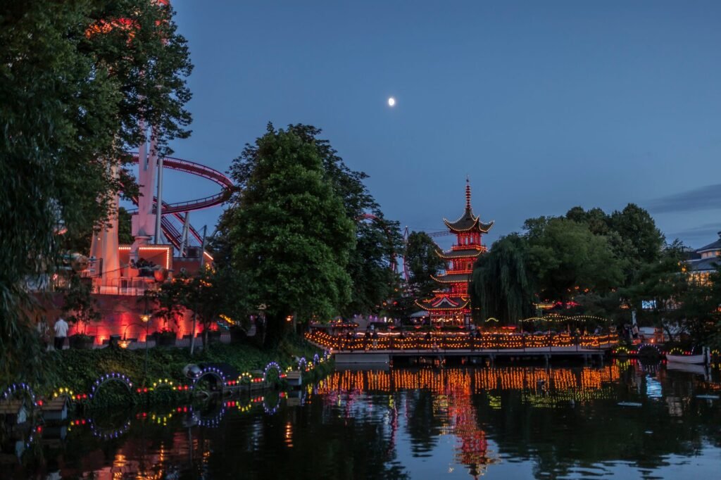 Illuminated pagoda and colourful lights reflected in water at Tivoli Gardens in Copenhagen.