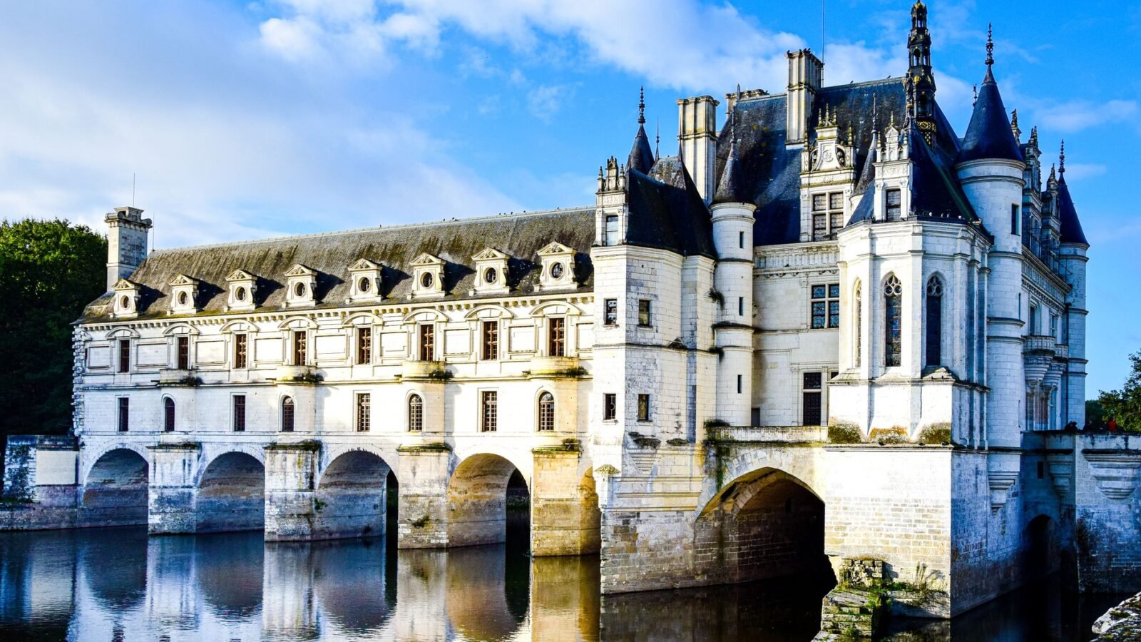 Château de Chenonceau spanning the River Cher beneath a pale sky in France.