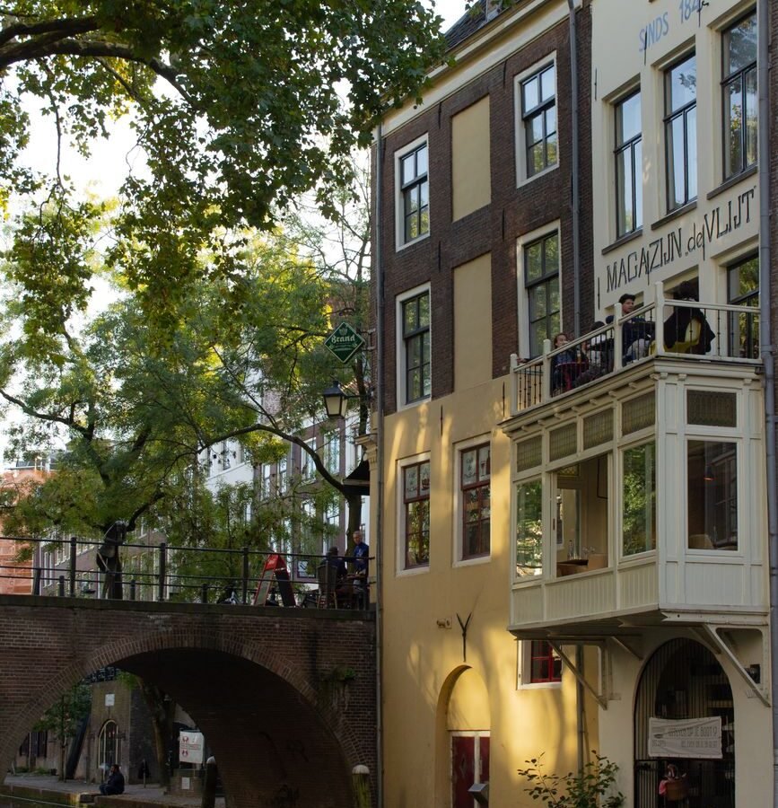 Historic brick buildings and trees reflected in a canal in central Utrecht, Netherlands.