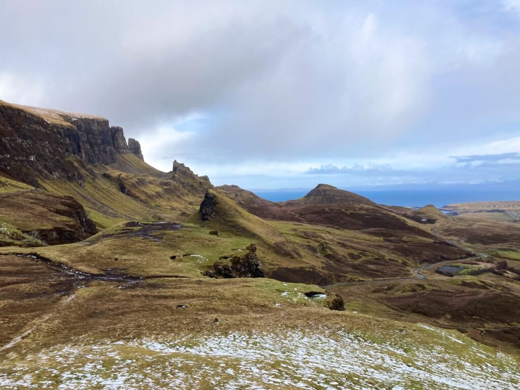Layered green ridges and rocky formations of the Quiraing overlooking the Isle of Skye coast.