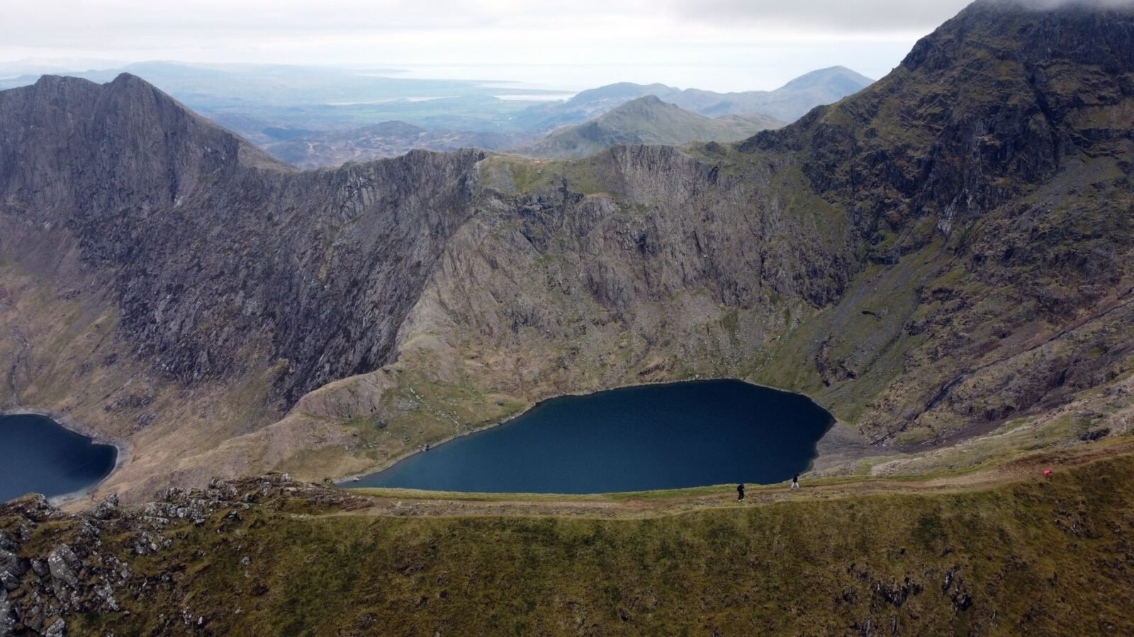 Yr Wyddfa mountain ridges rising above blue lakes and green valleys beneath broken cloud in Wales.