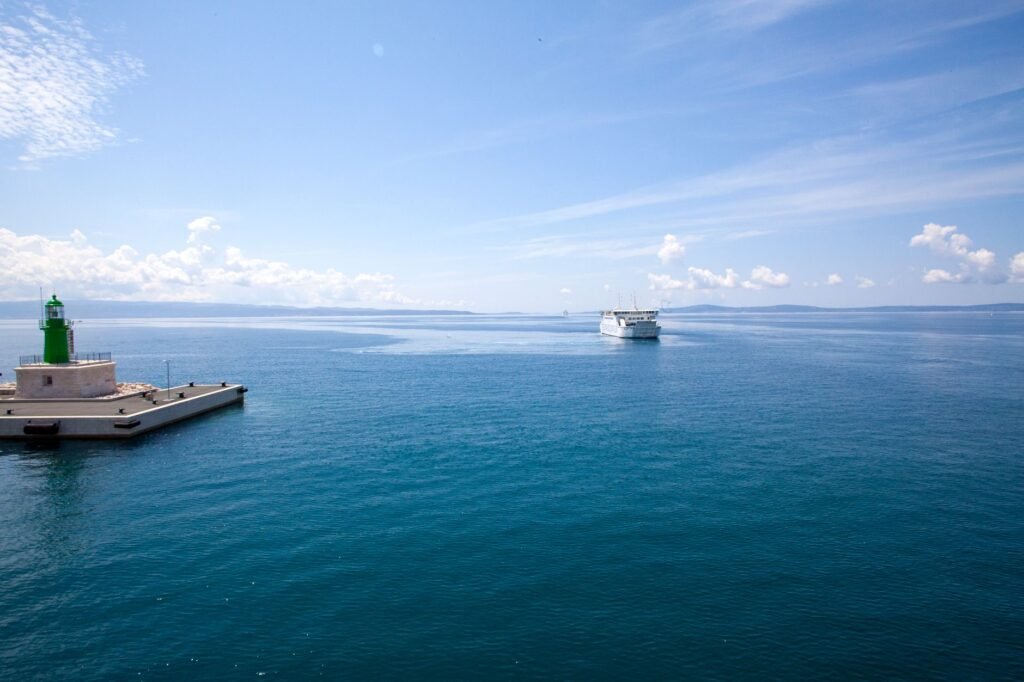 White passenger ferry travelling across blue water near the rocky Croatian coast by Split.