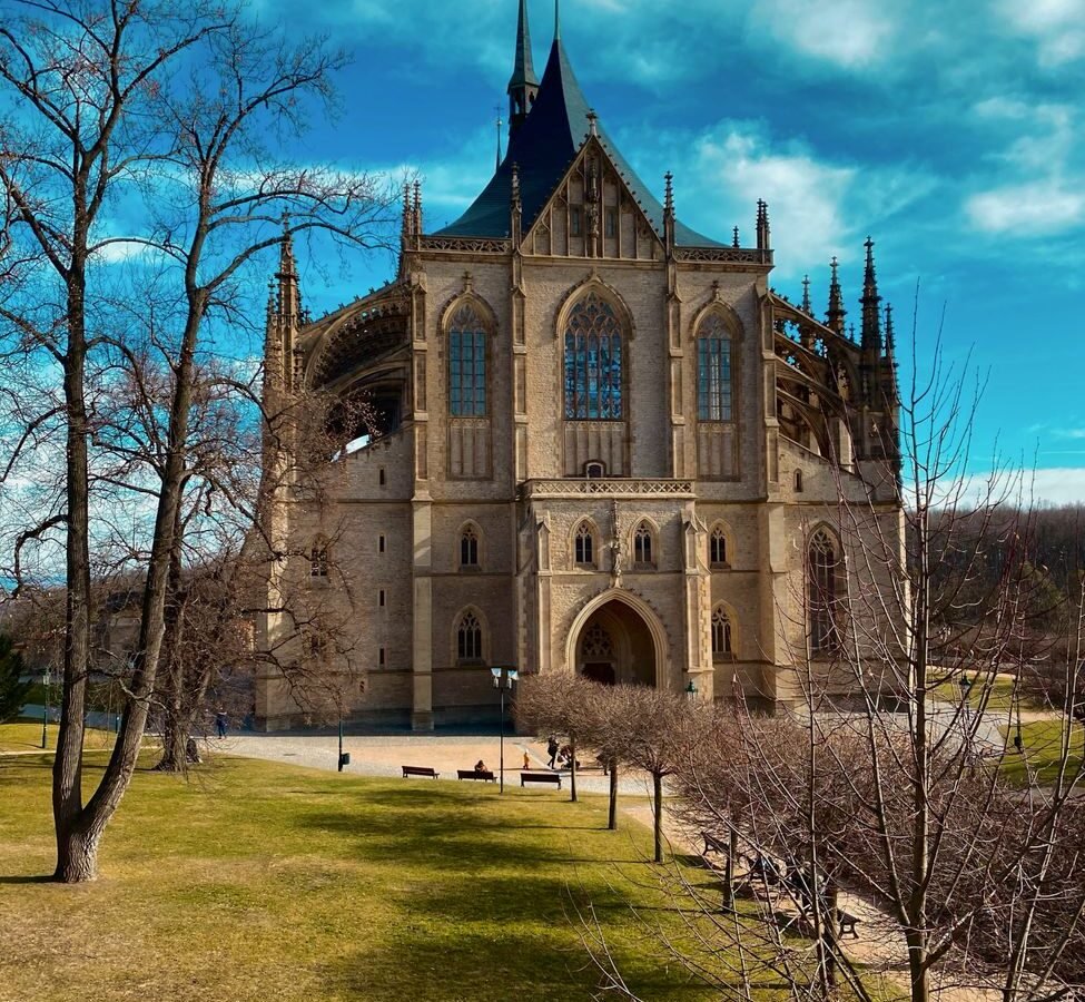 Gothic exterior of St Barbara's Cathedral in Kutna Hora, Czech Republic, beneath a blue sky.