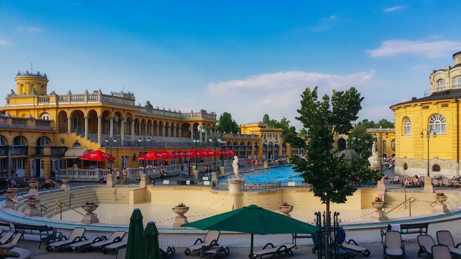 Outdoor pools and pale yellow neoclassical buildings at Szechenyi Thermal Bath in Budapest, Hungary.