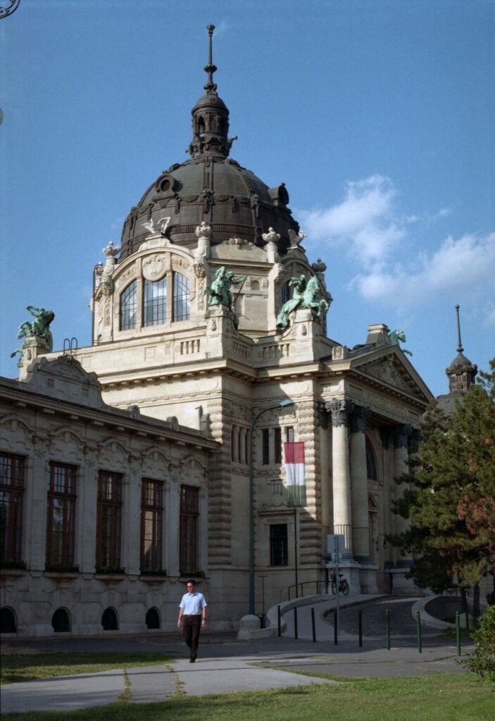 Tall yellow facade and outdoor pool at Szechenyi Bath in Budapest.
